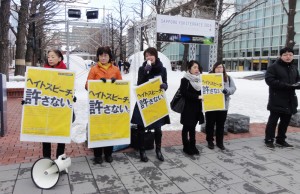 法務省の啓発ポスターを掲げ、訴える太田（中央）、池田（その左）両札幌市議ら=6日、札幌市